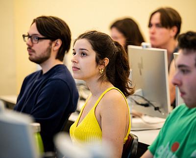 Students sit in front of computers in a classroom.